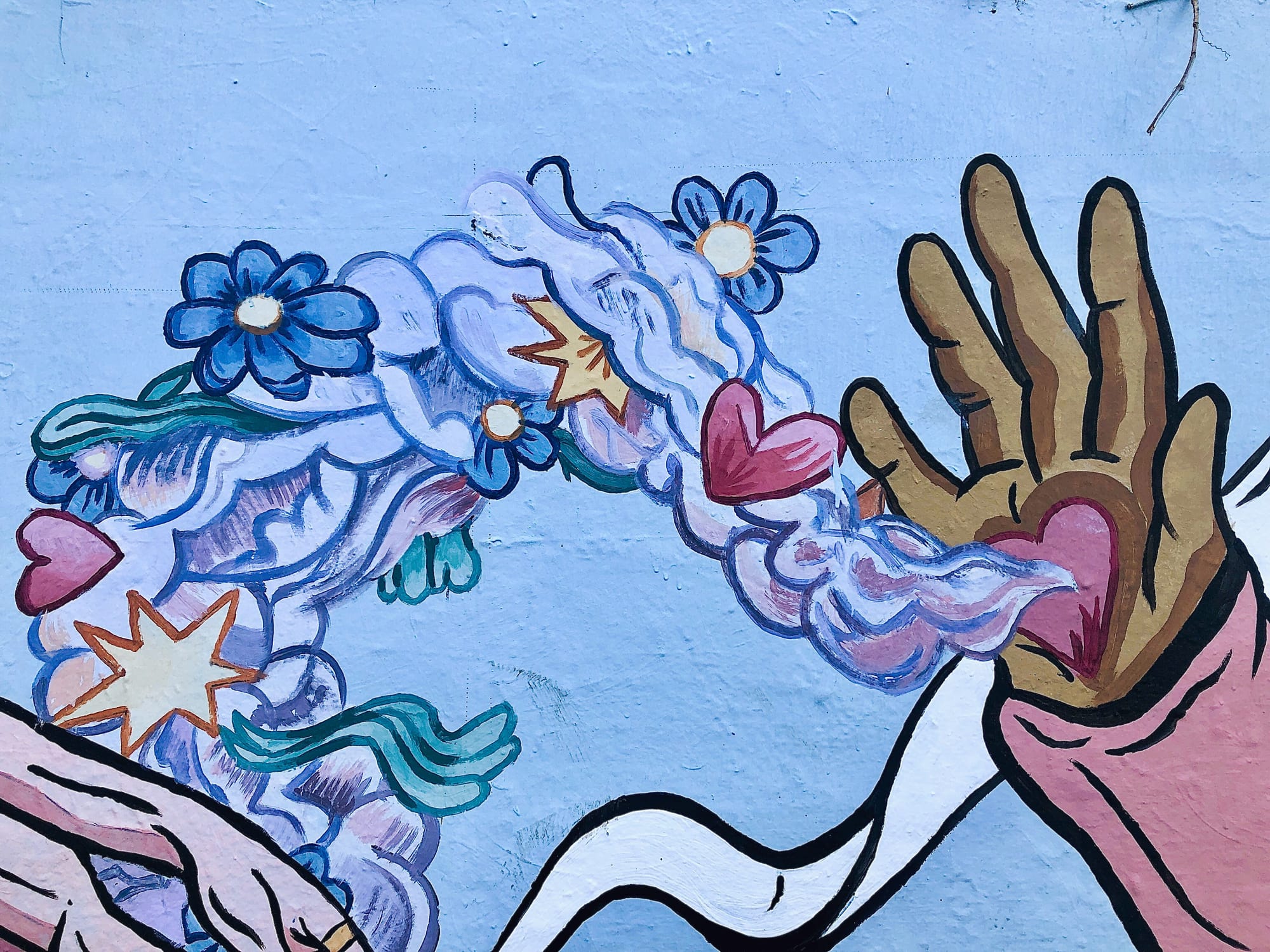 A painted mural of a hand sharing hearts, flowers and stars